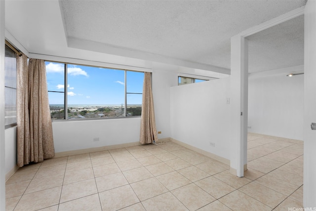 spare room with a textured ceiling and light tile patterned floors