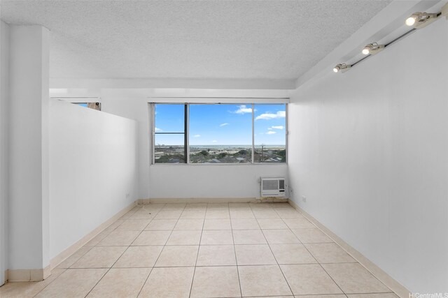 spare room with a textured ceiling, a wall mounted AC, and light tile patterned floors