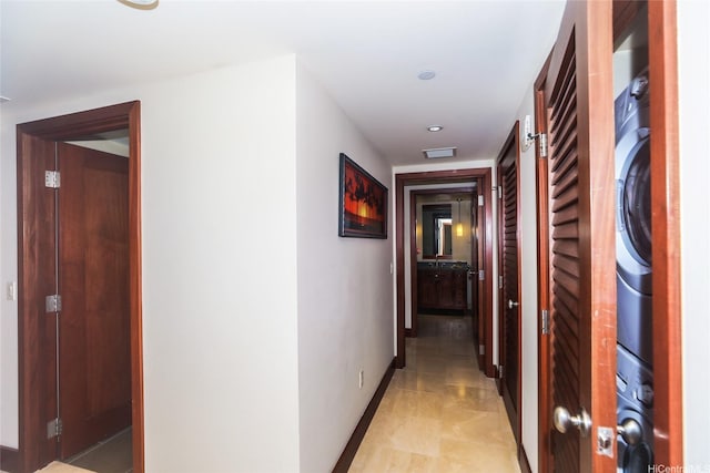 corridor with baseboards, stacked washer and clothes dryer, visible vents, and recessed lighting