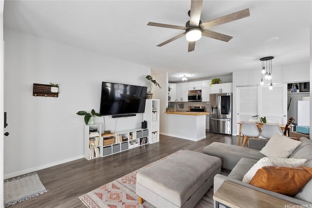 living area featuring baseboards, dark wood finished floors, and ceiling fan