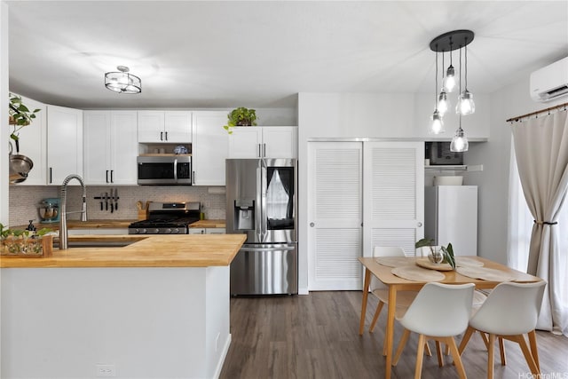 kitchen with a sink, stainless steel appliances, butcher block counters, an AC wall unit, and decorative backsplash