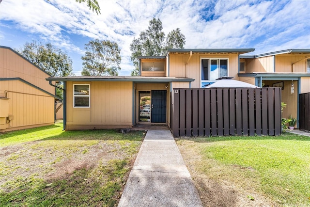 view of front facade featuring a front yard and fence