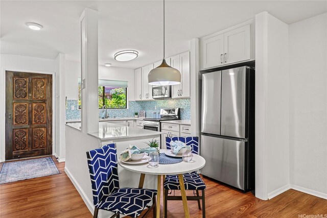 98-1790 Kaahumanu St Unit 64B, Pearl City, HI 96782 - kitchen with stainless steel appliances, light countertops, a sink, wood finished floors, and baseboards