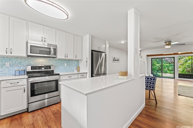 kitchen featuring ceiling fan, appliances with stainless steel finishes, light wood-style floors, and white cabinets
