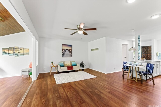 living area featuring wood finished floors, visible vents, baseboards, and ceiling fan