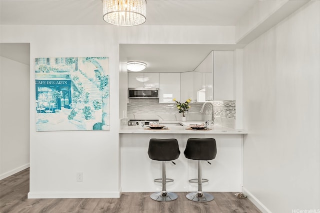 1433 Kewalo St Unit Ph12, Honolulu, HI 96822 - kitchen featuring tasteful backsplash, stainless steel microwave, light countertops, and a kitchen breakfast bar