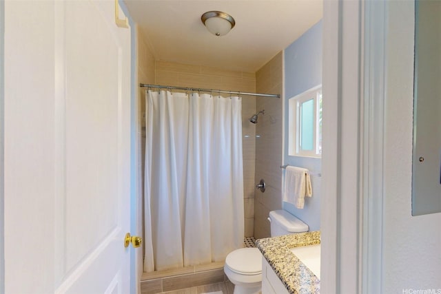 full bathroom featuring tiled shower, vanity, and toilet