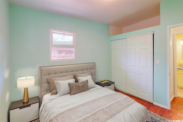 bedroom with wood finished floors, a closet, and baseboards