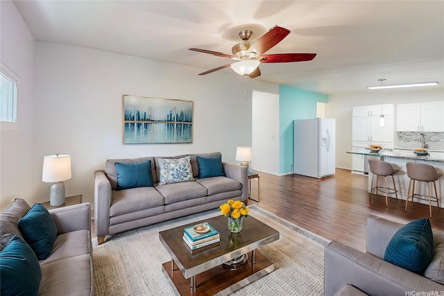 living area featuring dark wood-style flooring, baseboards, and a ceiling fan