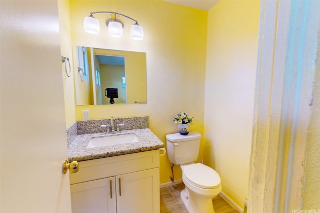 bathroom featuring toilet, vanity, and baseboards