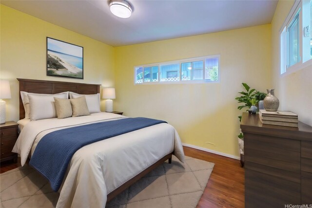 bedroom with multiple windows, baseboards, and wood finished floors