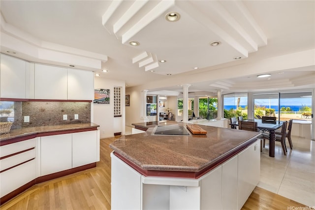 31 Poipu Dr, Honolulu, HI 96825 - kitchen featuring white cabinets, dark stone countertops, a raised ceiling, decorative backsplash, and decorative columns