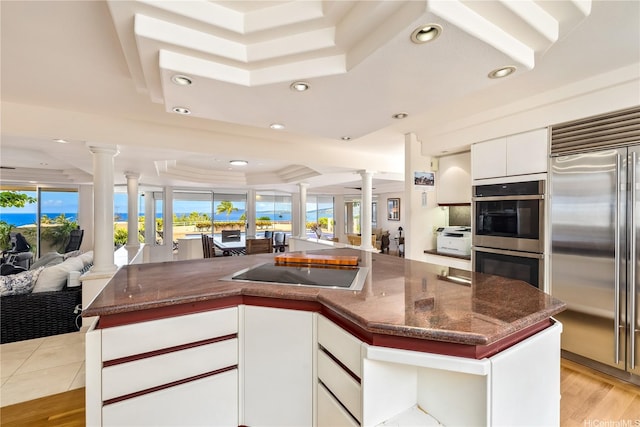 31 Poipu Dr, Honolulu, HI 96825 - kitchen with a tray ceiling, open floor plan, white cabinetry, ornate columns, and appliances with stainless steel finishes