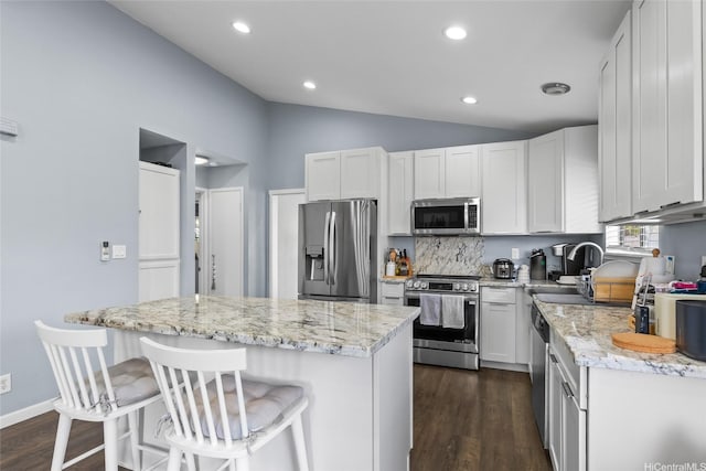 94-1106 Kaloli Loop, Waipahu, HI 96797 - kitchen featuring stainless steel appliances, vaulted ceiling, a center island, dark wood-type flooring, and light stone countertops