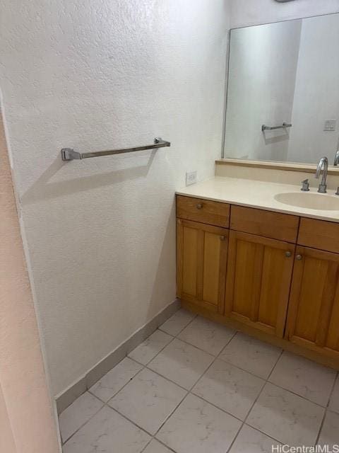 1920 Ala Moana Blvd Unit 1210, Honolulu, HI 96815 - bathroom featuring vanity, baseboards, a textured wall, and marble look tile flooring