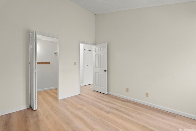 94-441 Kauopua St, Mililani, HI 96789 - unfurnished bedroom with a spacious closet, light wood-style floors, baseboards, a closet, and high vaulted ceiling