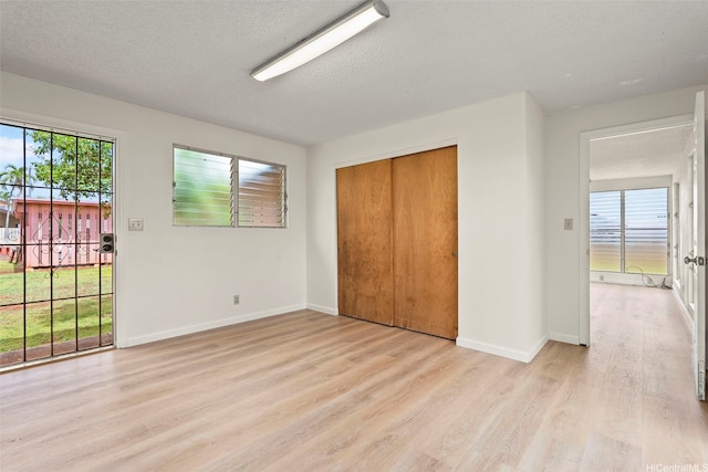 94-441 Kauopua St, Mililani, HI 96789 - unfurnished bedroom featuring light wood-style flooring, baseboards, a textured ceiling, a closet, and access to outside