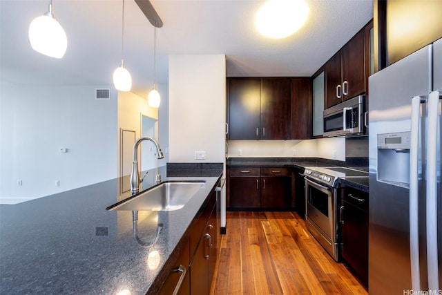 1189 Waimanu St Unit 2803, Honolulu, HI 96814 - kitchen featuring appliances with stainless steel finishes, a sink, decorative light fixtures, dark brown cabinetry, and wood finished floors