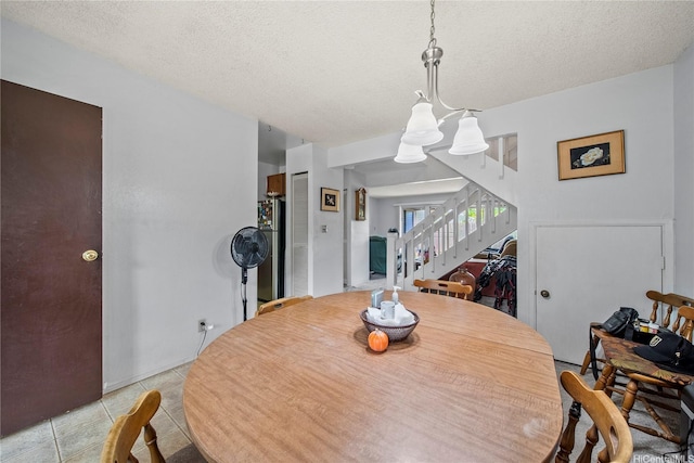 dining area featuring stairs, light tile patterned flooring, a textured ceiling, and a chandelier