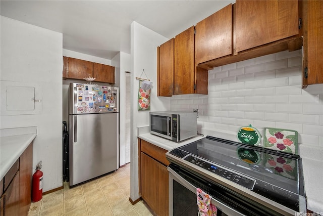 kitchen with light countertops, tasteful backsplash, stainless steel appliances, and brown cabinets