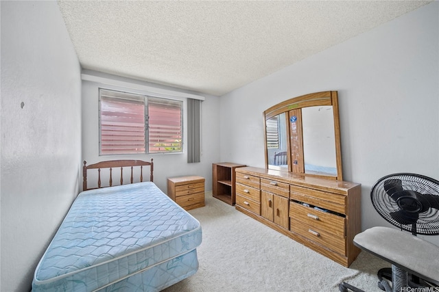 bedroom featuring a textured ceiling, light carpet, and multiple windows