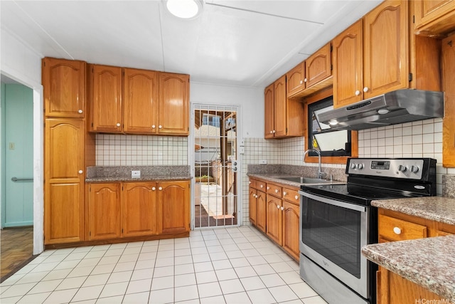 kitchen featuring stainless steel electric stove, under cabinet range hood, a sink, brown cabinetry, and tasteful backsplash