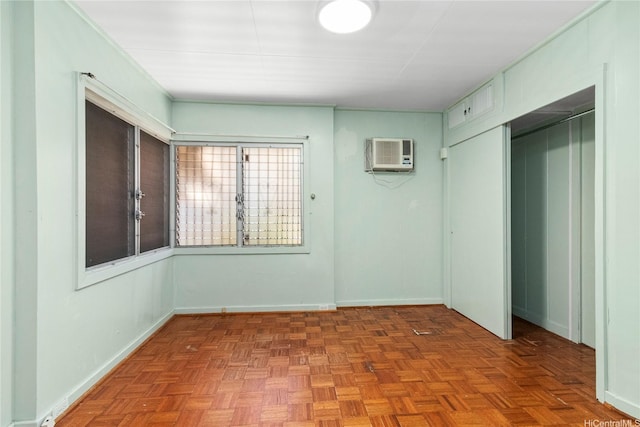 unfurnished bedroom with a wall unit AC, a closet, and baseboards