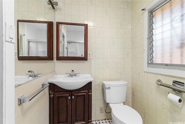 bathroom with toilet, tile walls, and vanity