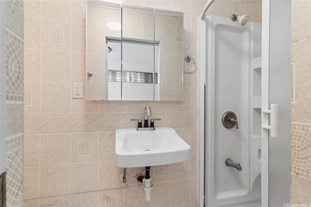 full bathroom with a shower, tile walls, and a sink