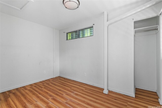 unfurnished bedroom with wood finished floors, a closet, and baseboards