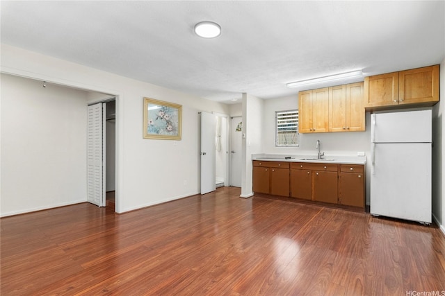 kitchen featuring freestanding refrigerator, light countertops, a sink, dark wood finished floors, and baseboards