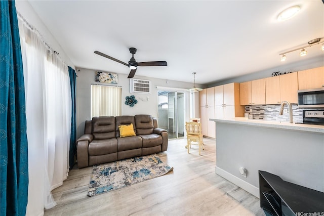 living area with baseboards, a ceiling fan, and light wood finished floors