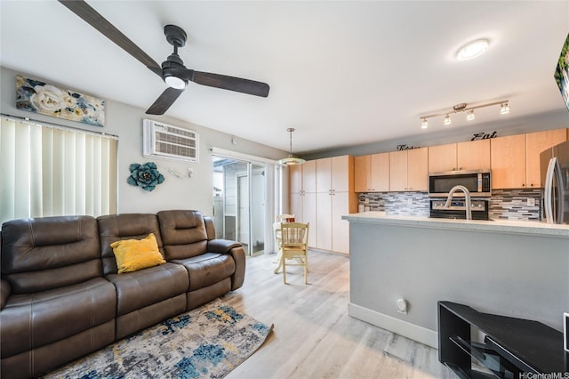 living room with a ceiling fan, light wood-style flooring, and a wall mounted air conditioner