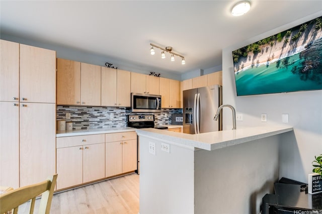 kitchen with light brown cabinetry, appliances with stainless steel finishes, a sink, light countertops, and tasteful backsplash