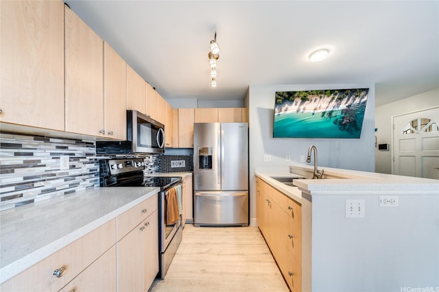 kitchen with a sink, light brown cabinets, stainless steel appliances, light wood-type flooring, and backsplash
