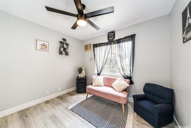 sitting room featuring light wood-style floors, a wall mounted air conditioner, baseboards, and ceiling fan