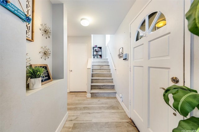 hall featuring stairway, baseboards, and light wood finished floors