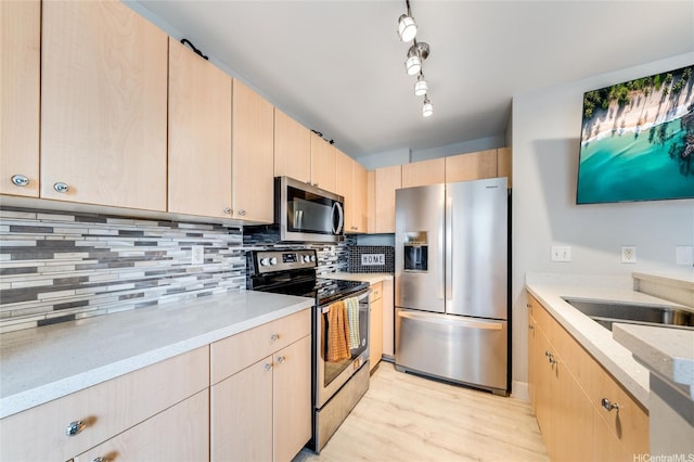 kitchen featuring light brown cabinetry, stainless steel appliances, tasteful backsplash, and light wood-type flooring