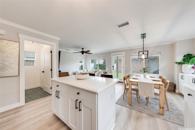 91-1180 Waiemi St, Ewa Beach, HI 96706 - kitchen featuring light wood-style flooring, ornamental molding, a kitchen island, open floor plan, and white cabinets
