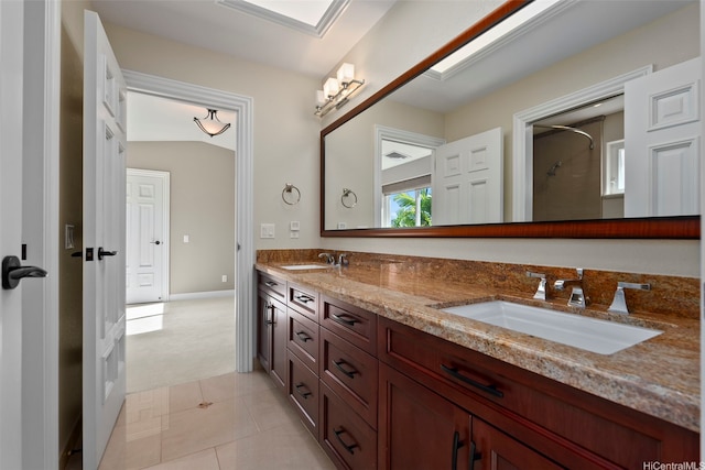 bathroom featuring tile patterned floors, walk in shower, double vanity, and a sink
