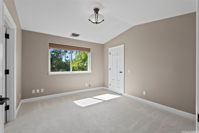 unfurnished bedroom featuring visible vents, light colored carpet, baseboards, and lofted ceiling