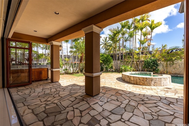 view of patio featuring fence, an in ground hot tub, and glass enclosure