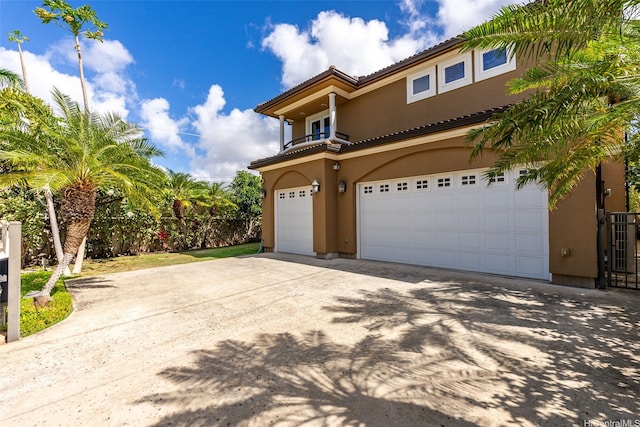 view of front of home featuring a tiled roof, a garage, concrete driveway, stucco siding, and a balcony