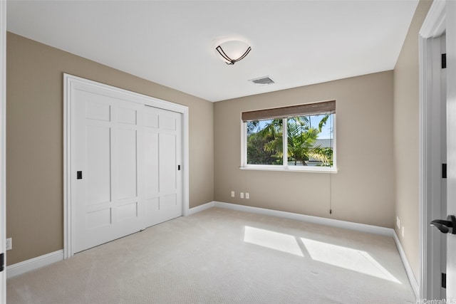 unfurnished bedroom with visible vents, baseboards, a closet, and light colored carpet
