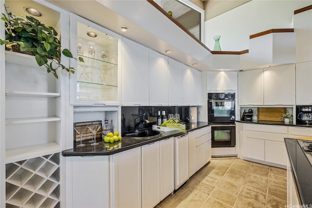 kitchen featuring dobule oven black, white cabinetry, a sink, and dark countertops