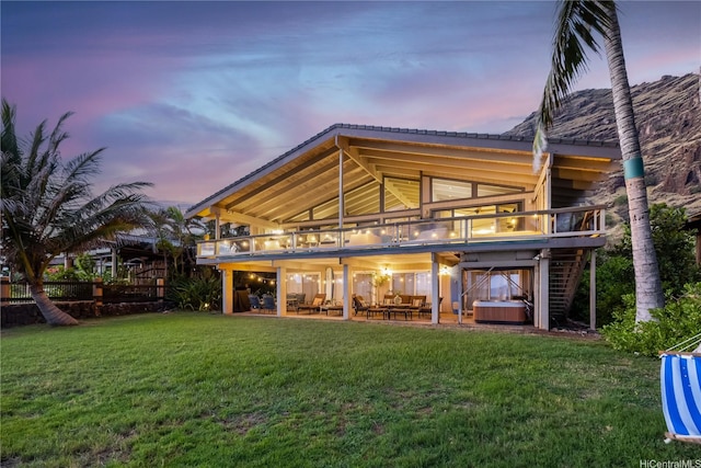 back of property featuring a patio, a yard, and a hot tub