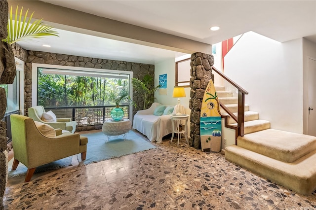sitting room featuring stairway and stone finish floor