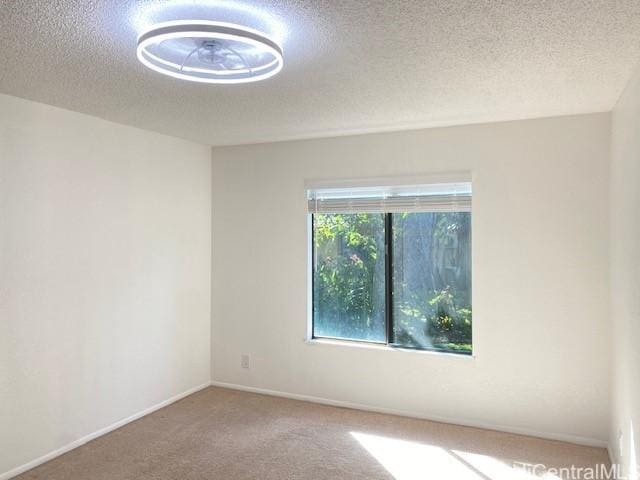 carpeted empty room featuring a textured ceiling and baseboards