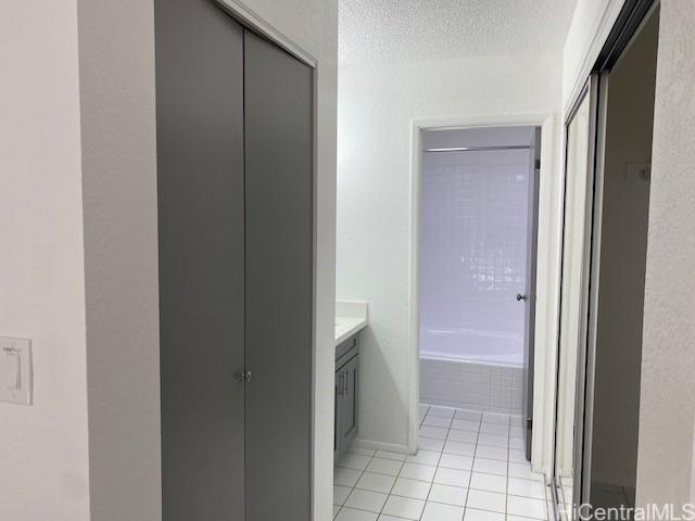 bathroom featuring a tub, a textured ceiling, tile patterned flooring, walk in shower, and vanity