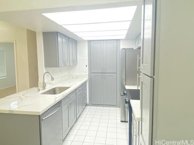kitchen with gray cabinetry, light tile patterned flooring, appliances with stainless steel finishes, and a sink
